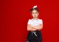 Portrait of a cute little girl in a white T-shirt and black skirt on a red background. Royalty Free Stock Photo