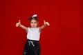 Portrait of a cute little girl in a white T-shirt and black skirt on a red background. Royalty Free Stock Photo