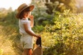 Portrait of cute little girl is smelling wild flower and walks in the rays of a sunset in a flowering meadow, enjoying Royalty Free Stock Photo