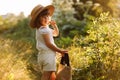 Portrait of cute little girl is smelling wild flower and walks in the rays of a sunset in a flowering meadow, enjoying Royalty Free Stock Photo