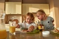 Portrait of cute little girl watching her brother spreading chocolate butter on toasted bread while preparing lunch or Royalty Free Stock Photo