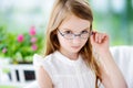 Portrait of cute little girl wearing glasses at home. Vision, health, ophthalmology concept.