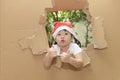 Cute little girl wearing a Santa hat thumbs up.in the torn paper wall Royalty Free Stock Photo