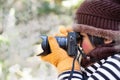 Portrait of a cute little girl in Wool hat taking a picture with digital camera at the weather is cold on blurred background Royalty Free Stock Photo