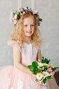 Portrait of a cute little girl in a wreath of flowers and a beautiful bouquet of flowers in a bright studio Royalty Free Stock Photo