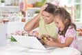Portrait of cute little girl with young mother playing computer game with laptop Royalty Free Stock Photo