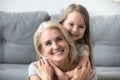 Portrait of smiling granddaughter piggyback grandmother at home Royalty Free Stock Photo