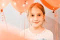 Portrait of a cute little happy candid smiling caucasian eight year old kid girl with red balloons against the background of a gra Royalty Free Stock Photo