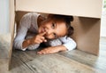 Portrait of a cute little hispanic girl playing with a cardboard box in a new apartment. Cute mixed race girl hiding in Royalty Free Stock Photo