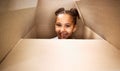 Portrait of a cute little hispanic girl playing with a cardboard box in a new apartment. Cute mixed race girl hiding in Royalty Free Stock Photo