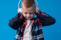 Portrait of a cute little kid in headphones listening to music over blue background Royalty Free Stock Photo