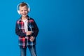 Portrait of a cute little kid in headphones listening to music over blue background Royalty Free Stock Photo