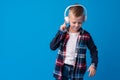 Portrait of a cute little kid in headphones listening to music over blue background Royalty Free Stock Photo
