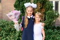 Portrait of a cute little seven year old first-grader girl with a bouquet of flowers with her younger brother ready to go to schoo Royalty Free Stock Photo