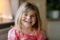 Portrait of cute little toddler girl with painted rainbow with colorful colors on face. Happy child with sign for Royalty Free Stock Photo