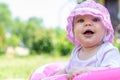 Portrait of a cute little toddler girl in pink panama in an outdoor inflatable pool in a country house in a village