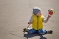 Portrait of cute little toddler sitting on asphalt and playing with balloon. Child outdoors