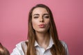 Portrait of cute lovely girl sending blowing kiss with pout lips looking at camera isolated on pink background Royalty Free Stock Photo