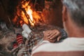 Portrait of cute mature senior enjoying Christmas in front of hot fireplace at home feeling cold embracing together and holding