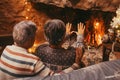 Portrait of cute mature senior enjoying Christmas in front of hot fireplace at home feeling cold embracing together and holding