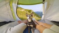 PORTRAIT: Cute miniature pinscher sits between hiker couple relaxing in tent.