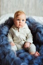 Portrait of cute 8 month old baby girl sitting on the bed on oversize knitted blanket Royalty Free Stock Photo