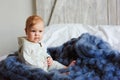 Portrait of cute 8 month old baby girl sitting on the bed on oversize knitted blanket Royalty Free Stock Photo