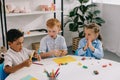 portrait of cute multiethnic preschoolers sculpturing figures with plasticine