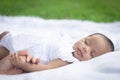 Portrait of cute new born baby girl is lie and holding her mother `s hand on the white cloth mattress in the lawn Royalty Free Stock Photo