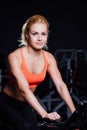 Portrait of a cute nice female workout on fitness the exercise bike dark at gym. Royalty Free Stock Photo