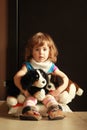 Portrait of a cute one year old girl sitting at home on a pillow on the floor and hugging her favourite toys - dogs. Royalty Free Stock Photo