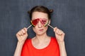 Portrait of cute perplexed young woman covering eyes with lollipops Royalty Free Stock Photo