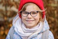 Portrait of a cute preschool girl with eye glasses and red hat outdoors. Happy funny child wearing new blue glasses Royalty Free Stock Photo