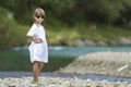 Portrait of cute pretty funny young girl with blond braids in white dress and dark sunglasses Royalty Free Stock Photo