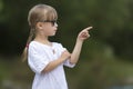 Portrait of cute pretty funny young girl with blond braids in white dress and dark sunglasses. Royalty Free Stock Photo