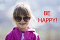 Portrait of cute pretty little blond preschool girl in pink sweater and dark sunglasses smiling happily in camera with funny Royalty Free Stock Photo