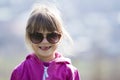 Portrait of cute pretty little blond preschool girl in pink sweater and dark sunglasses smiling happily in camera with funny child Royalty Free Stock Photo