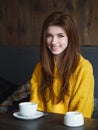 Portrait of a cute pretty redhead smiling woman sitting in a cafe enjoying free time coffee break with a cup of cappuccino