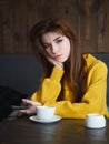 Portrait of a cute pretty redhead woman holding smartphone sitting in a cafe enjoying free time coffee break with a cup of Royalty Free Stock Photo
