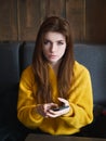 Portrait of a cute pretty redhead woman holding smartphone sitting in a cafe enjoying free time coffee break with a cup of Royalty Free Stock Photo