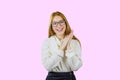 Portrait of a cute red-haired girl with glasses and a white sweater folded hands together holding them in the side Royalty Free Stock Photo
