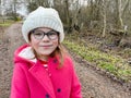 Portrait of a cute school girl with eyeglasses outdoors in park. Happy funny child on autumn, spring or winter day. Royalty Free Stock Photo