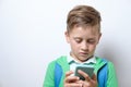 Portrait of a cute schoolboy with blue backpack and smart phone