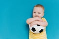 Portrait of cute shy blond little toddler boy in T-shirt holding football ball Royalty Free Stock Photo