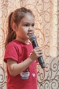 Portrait of cute shy little Asian girl holding microphone at home. Royalty Free Stock Photo