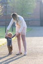 Portrait of cute small caucasian baby boy learn walking at the park holding mom hands, little toddler infant child make Royalty Free Stock Photo