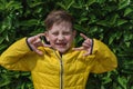 Portrait of Cute smiling boy 7 years old in a yellow jacket against a background of green natural texture Royalty Free Stock Photo