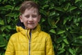 Portrait of Cute smiling boy 7 years old in a yellow jacket against a background of green natural texture Royalty Free Stock Photo