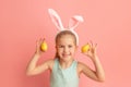 Portrait of cute smiling girl with Bunny ears and yellow Easter eggs, isolated on pink background. Happy Easter Royalty Free Stock Photo