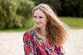 Portrait of a cute smiling girl with long blond hair blowing in the wind, in a red summer sundress on the beach Royalty Free Stock Photo